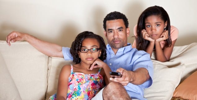 Dad watching TV with daughters