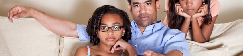 Dad watching TV with daughters