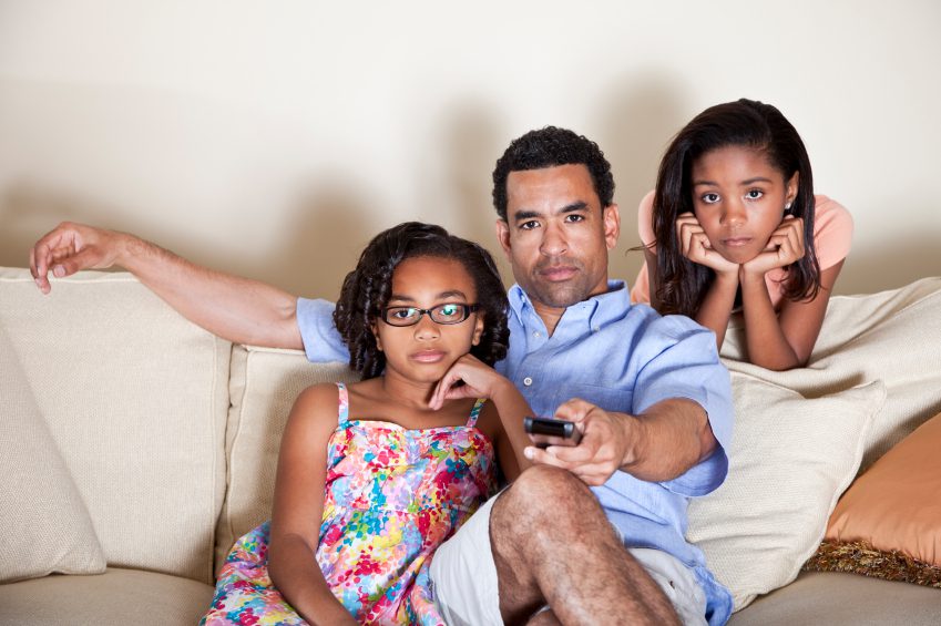 Dad watching TV with daughters
