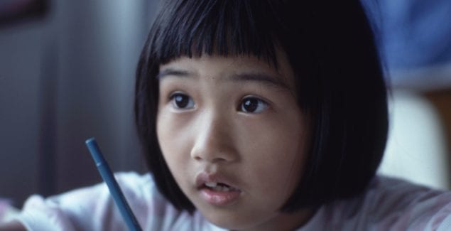 young girl looking up from writing