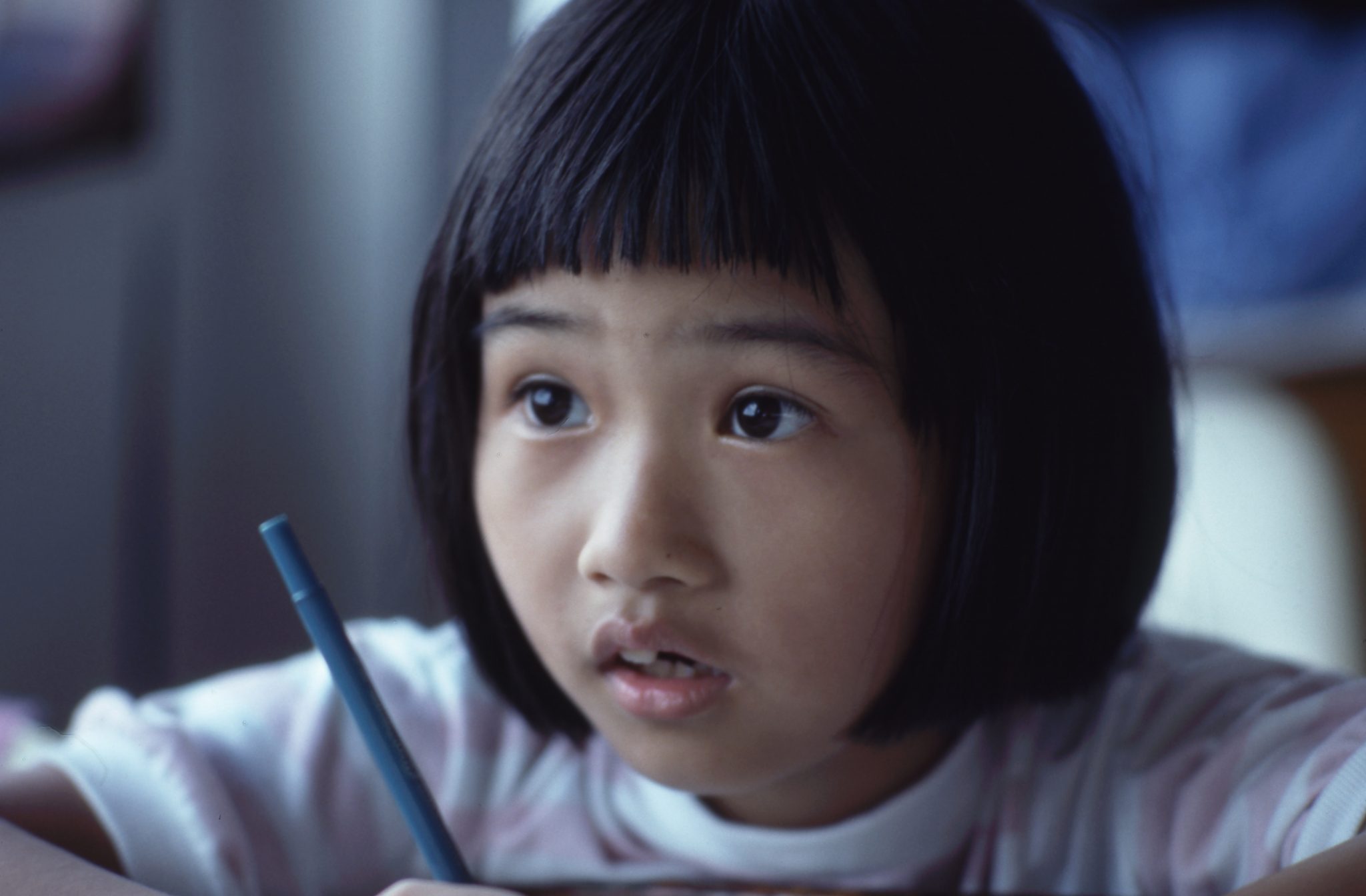 young girl looking up from writing