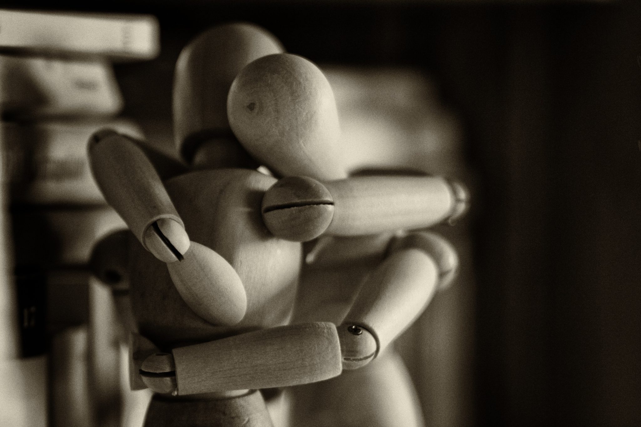 Mass shootings mental health - two wooden figures embracing in the shadows