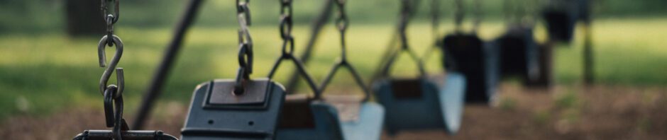 Photo of a row of swings in a playground, all empty