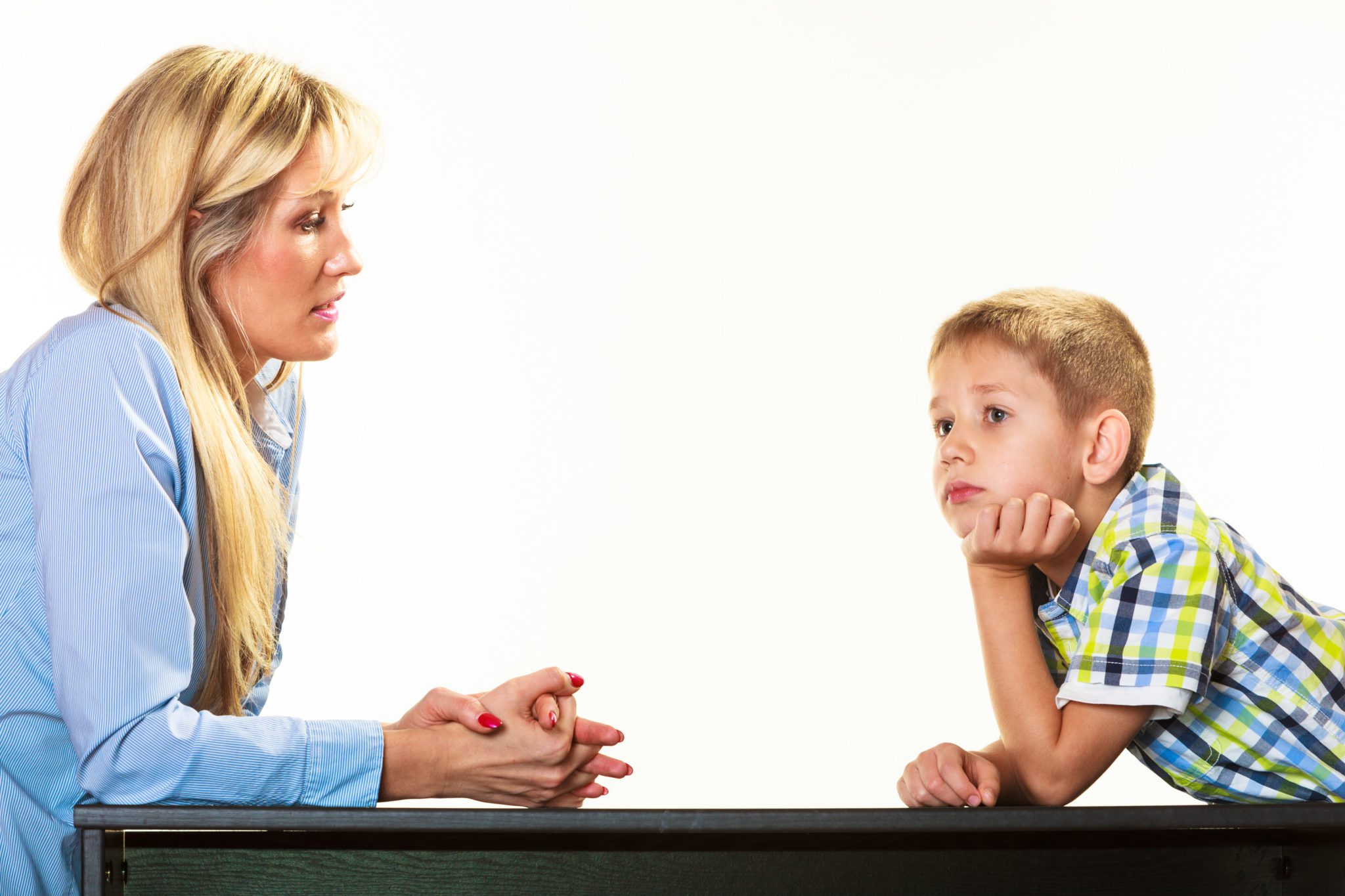 Mother sitting across table from grade-school-age son about to start a hard conversation