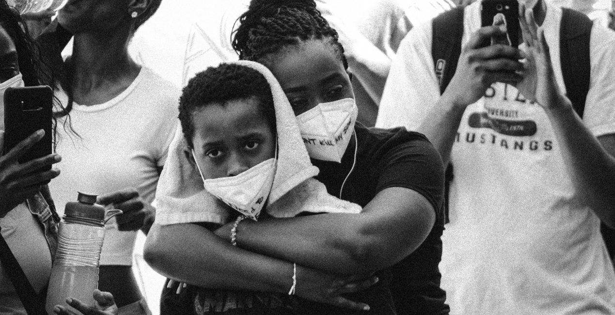 Black mother embracing at a Black Lives Matter / end racial violence protest - black & white