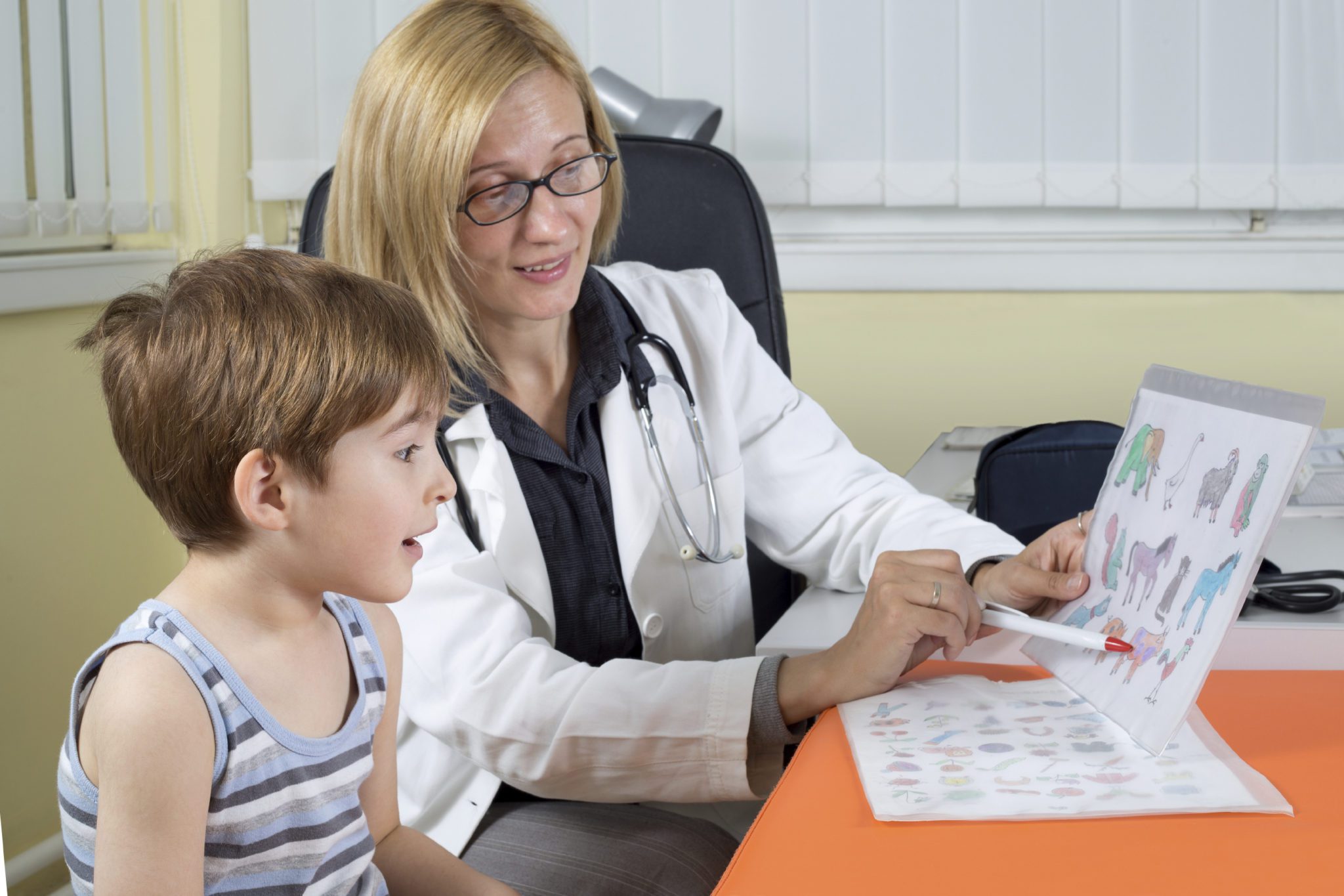 school evaluation - female child psychologist sits with grade school boy at a table