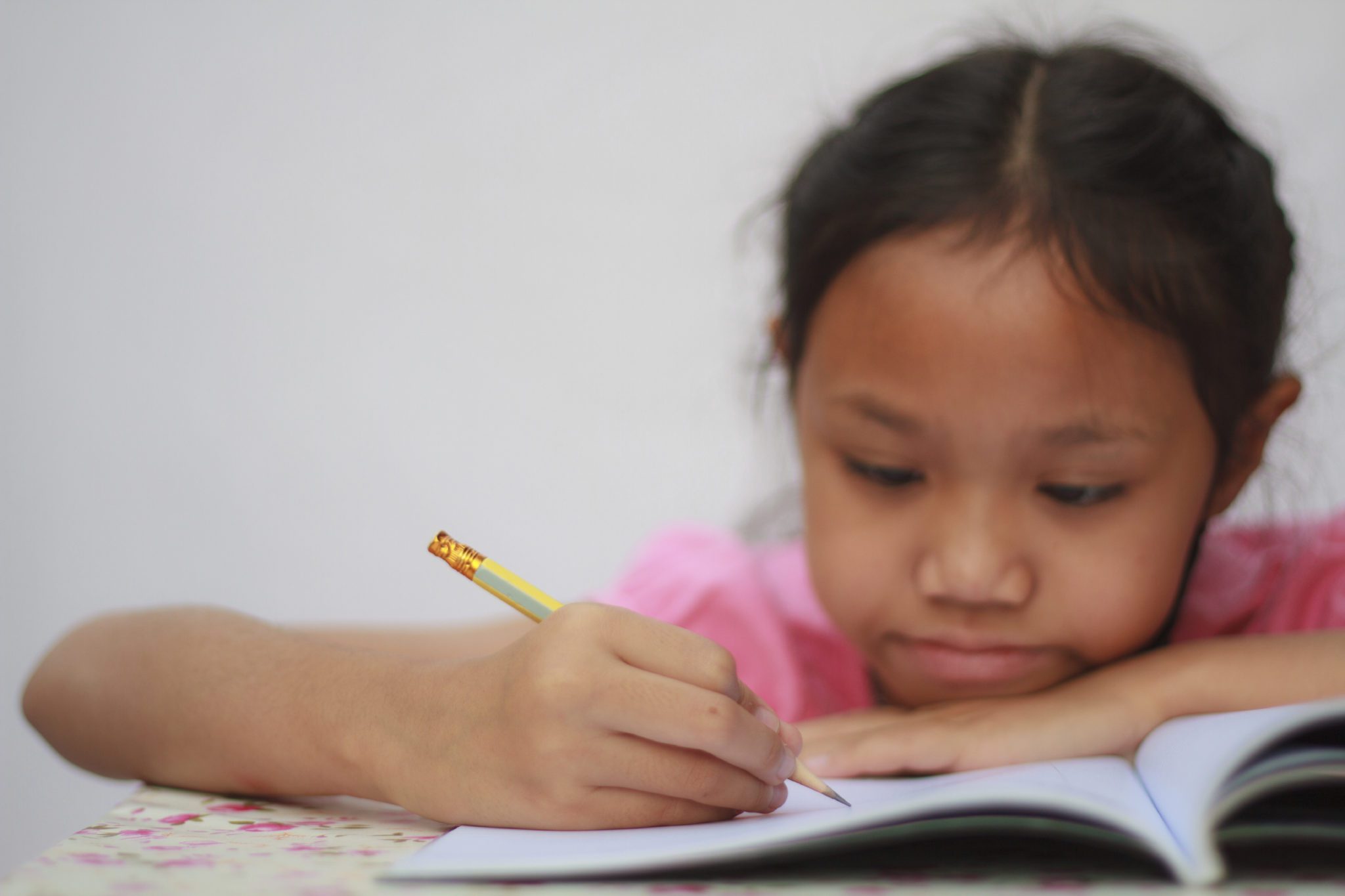Slow Processing Speed - Close up photo of young girl at desk writing in notebook focusing hard