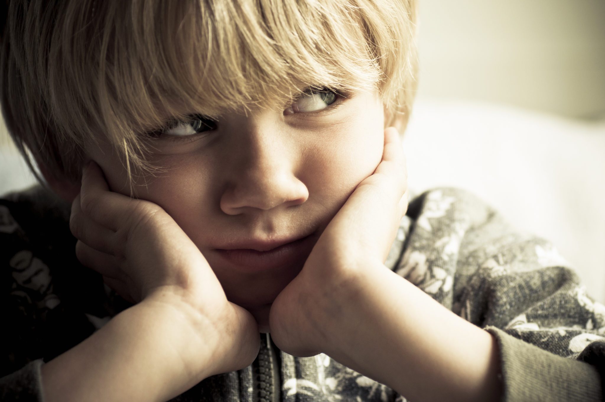 Specific Phobias - Young boy leaning his cheeks on his hands looking worried