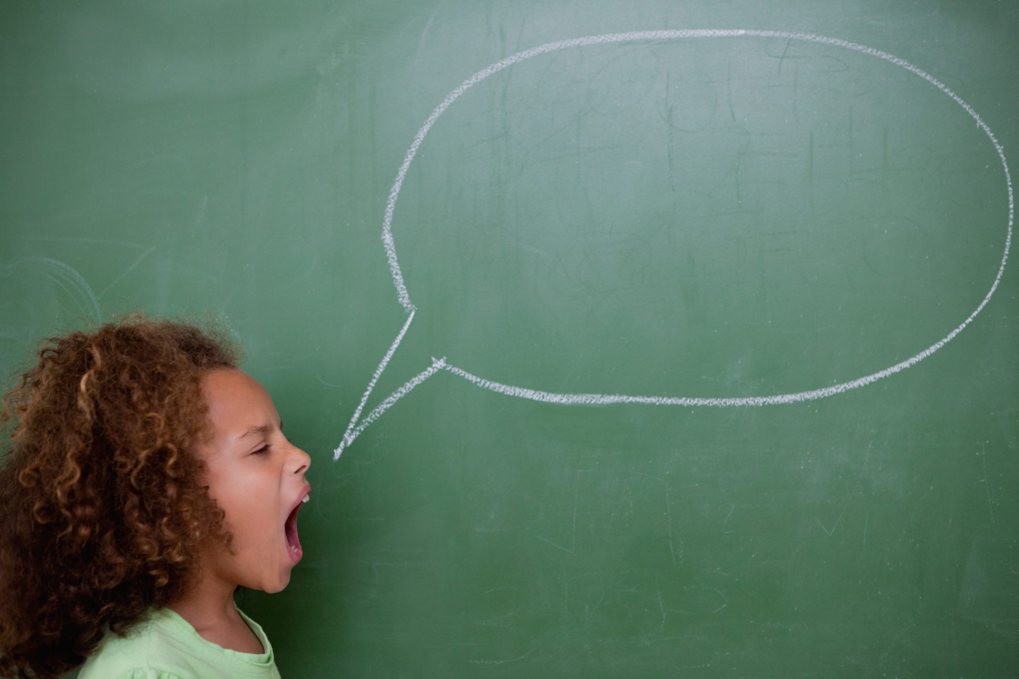 Schoolgirl screaming a speech bubble in front of a blackboard