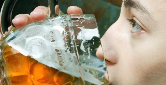 Drinking Problem - close up side view of teen drinking from a large glass of beer