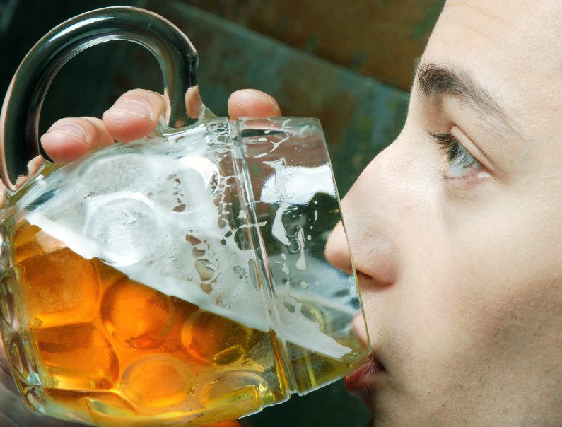 Drinking Problem - close up side view of teen drinking from a large glass of beer