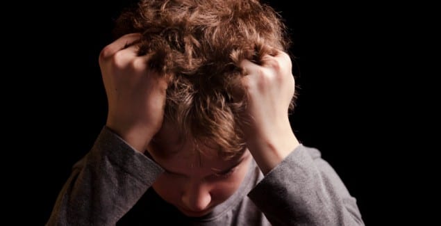 Child depression - Sad teenage boy on a black background