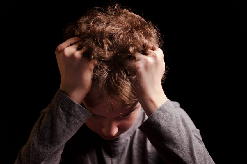 Child depression - Sad teenage boy on a black background